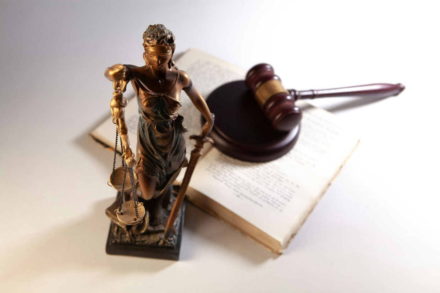 A figure of Justice holding scales, beside a gavel on an open book