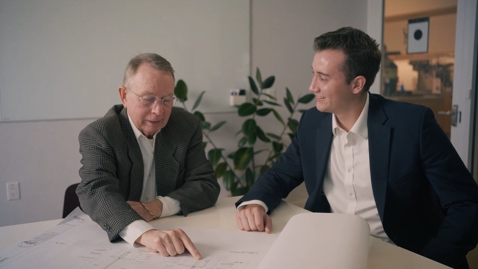 Two men at a table going over a set of drawings