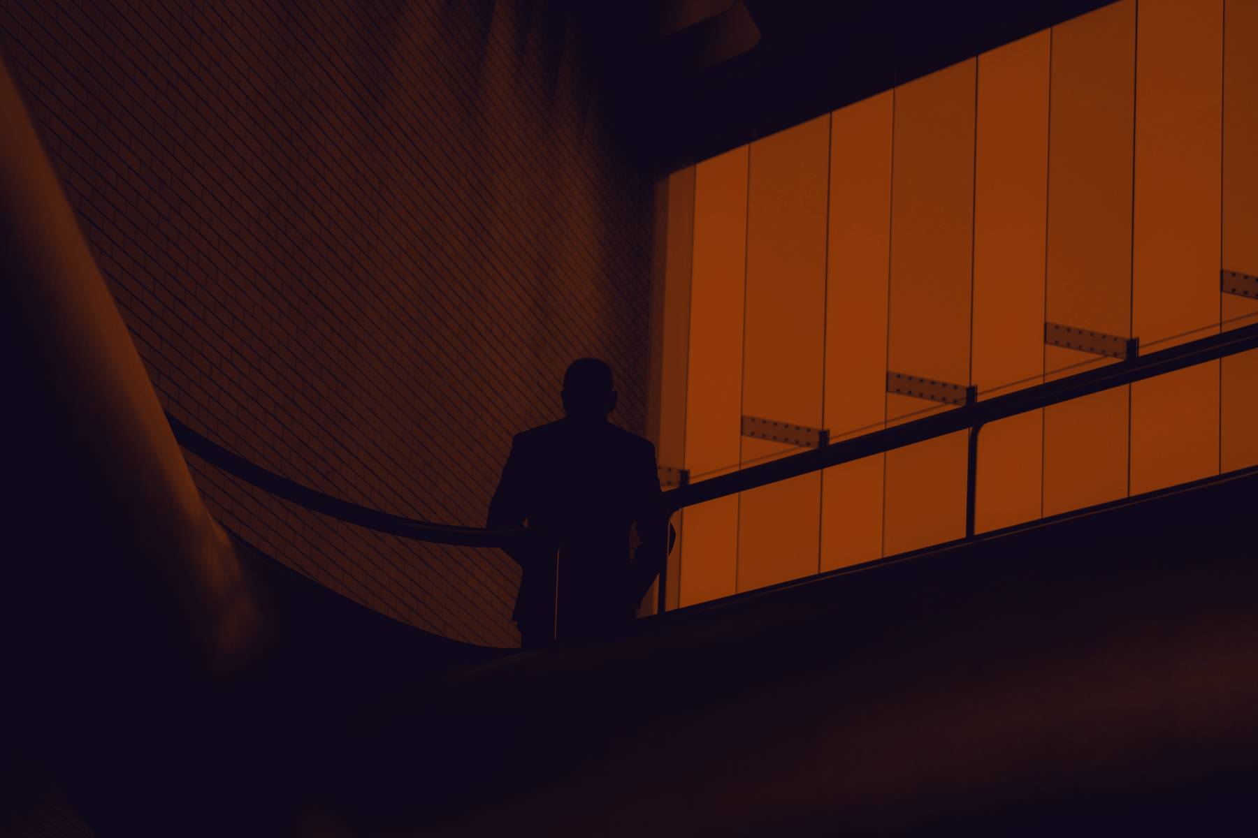 A man in a suit pausing on a curved staircase inside a lit building